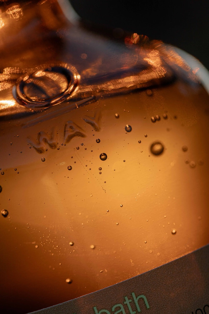 Macro sul prodotto contenuto all'interno del flacone in vetro ambrato Oway. La texture dello shampoo appare liquida con bollicine.